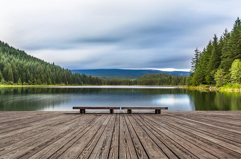 Boardwalk by a lake amongst mountains and forests